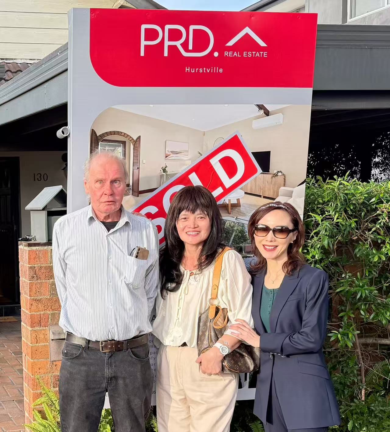 Three people pictured beside a SOLD sign